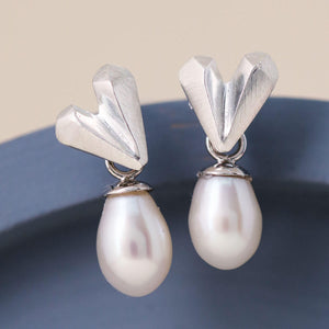 Heart pearl earrings in sterling silver displayed on a blue dish, showing faceted heart stud and white pearl drop, silver wedding earrings for bridesmaids
