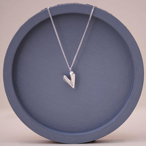 Heart shaped necklace product image on a blue dish showing the subtle sparkle of the faceted silver heart charm