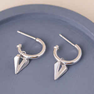 Silver hoop earrings with heart charm on a blue dish, handcrafted sterling silver hoops with hearts