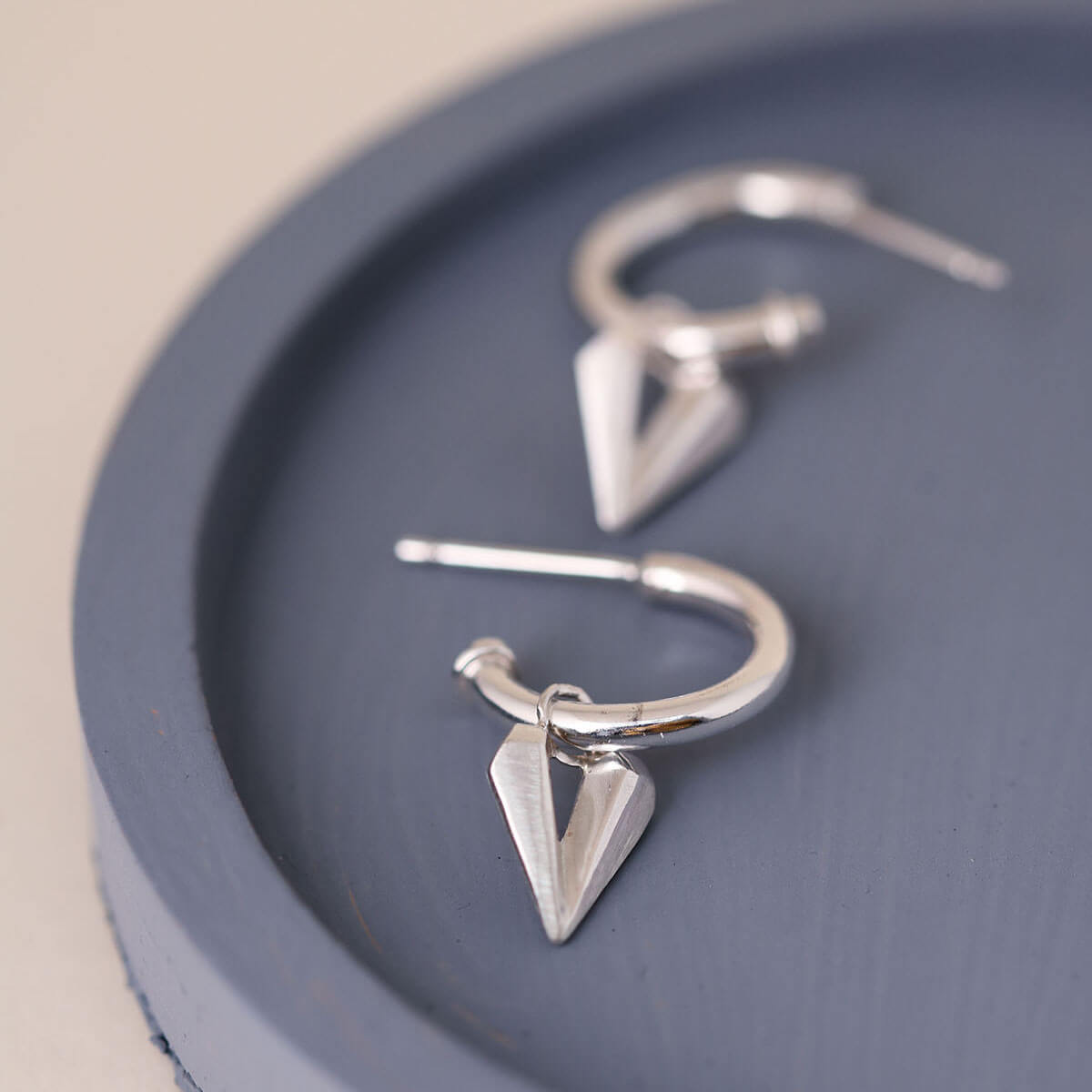 Silver hoop earrings with heart charm presented on a blue dish, versatile charm hoops with removable heart