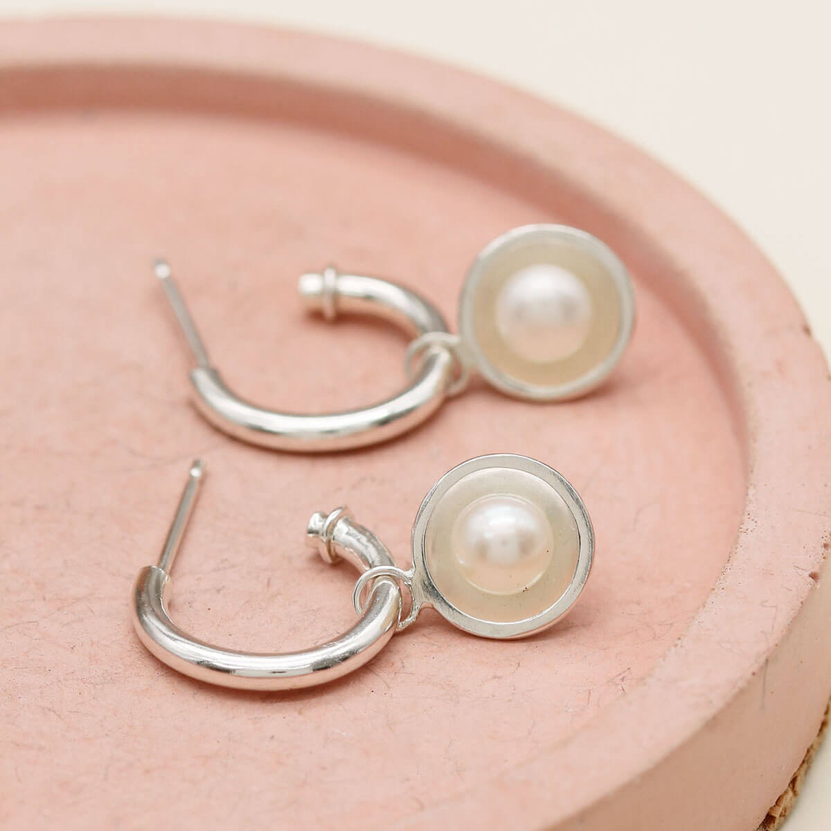 Silver hoop earrings with pearls featuring removable freshwater pearl charms and polished sterling silver hoops.