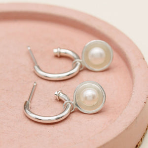 Silver hoop earrings with pearls featuring removable freshwater pearl charms and polished sterling silver hoops.