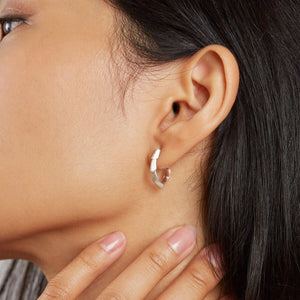 Woman wearing silver half hoop earrings in a second piercing, styled with other sterling silver stud earrings