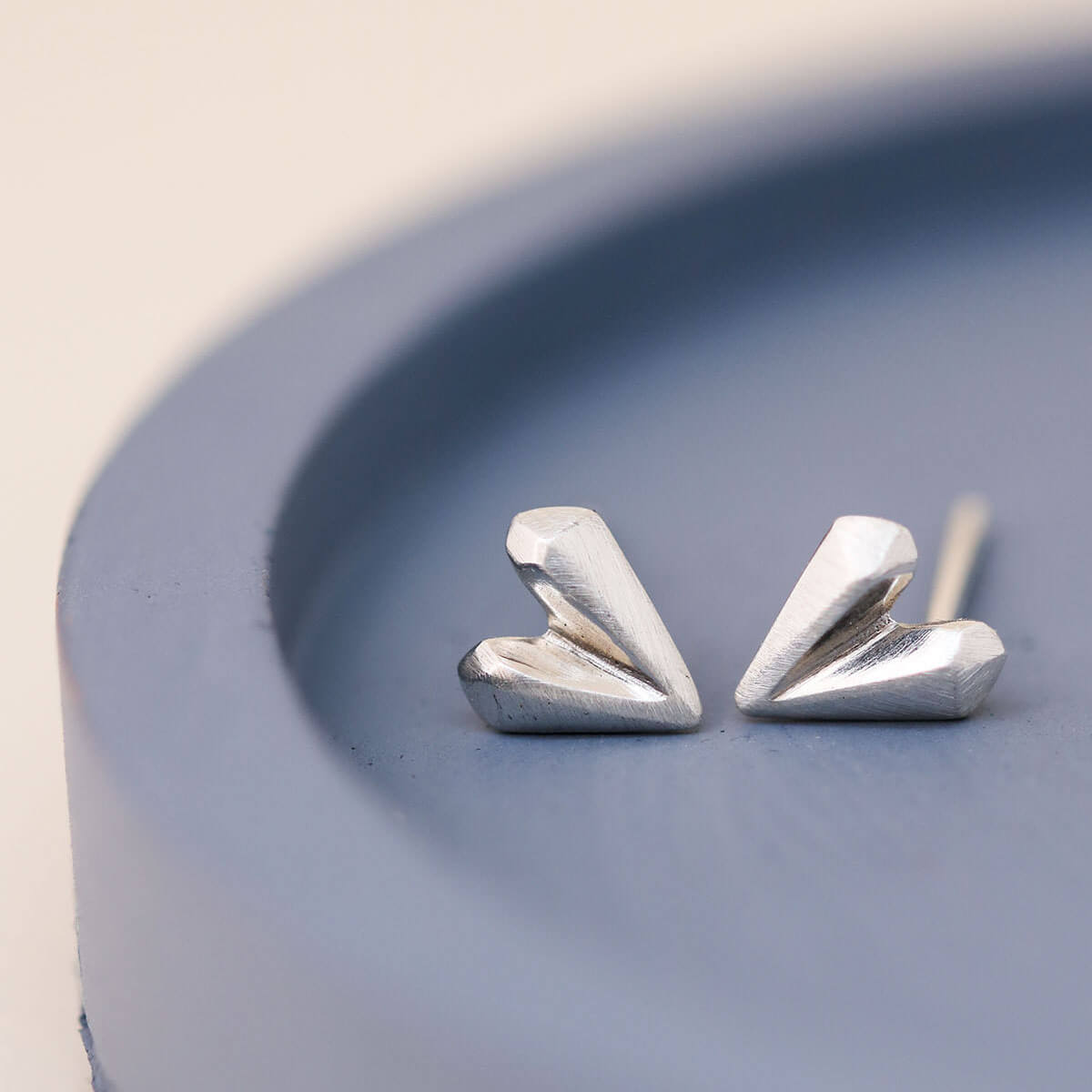 Love heart earrings in polished sterling silver on blue dish, classic silver heart stud earrings for romantic gifts