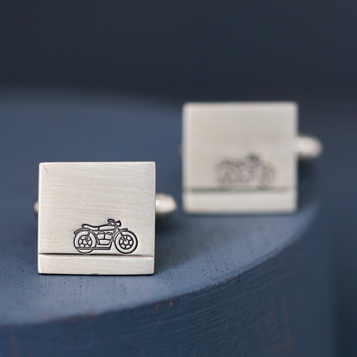 Close-up of sterling silver motorbike cufflinks on deep blue background, perfect wedding cufflinks for a motorbike lover