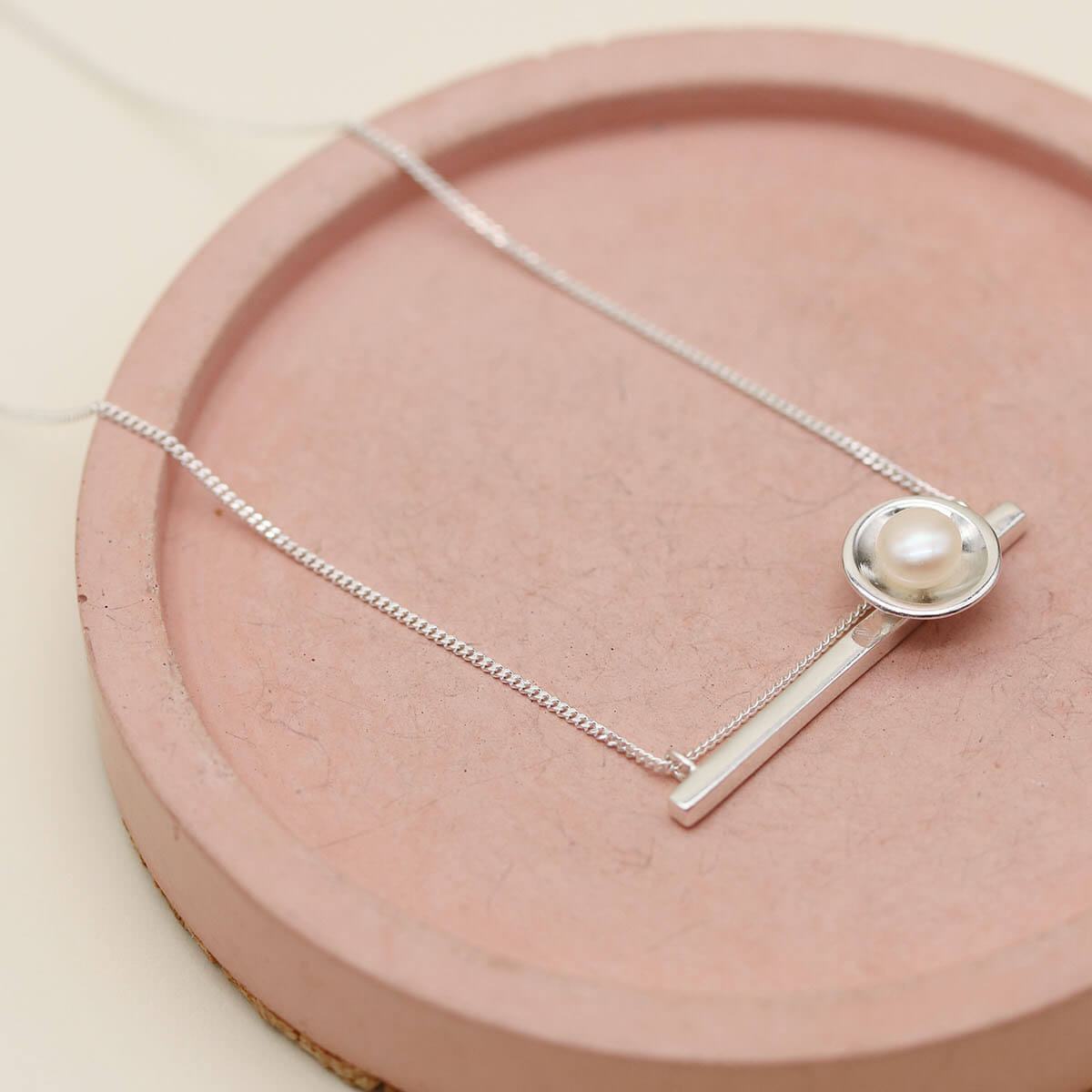 Handmade sterling silver geometric pearl necklace showing the chain running alongside the horizontal bar for a modern finish.