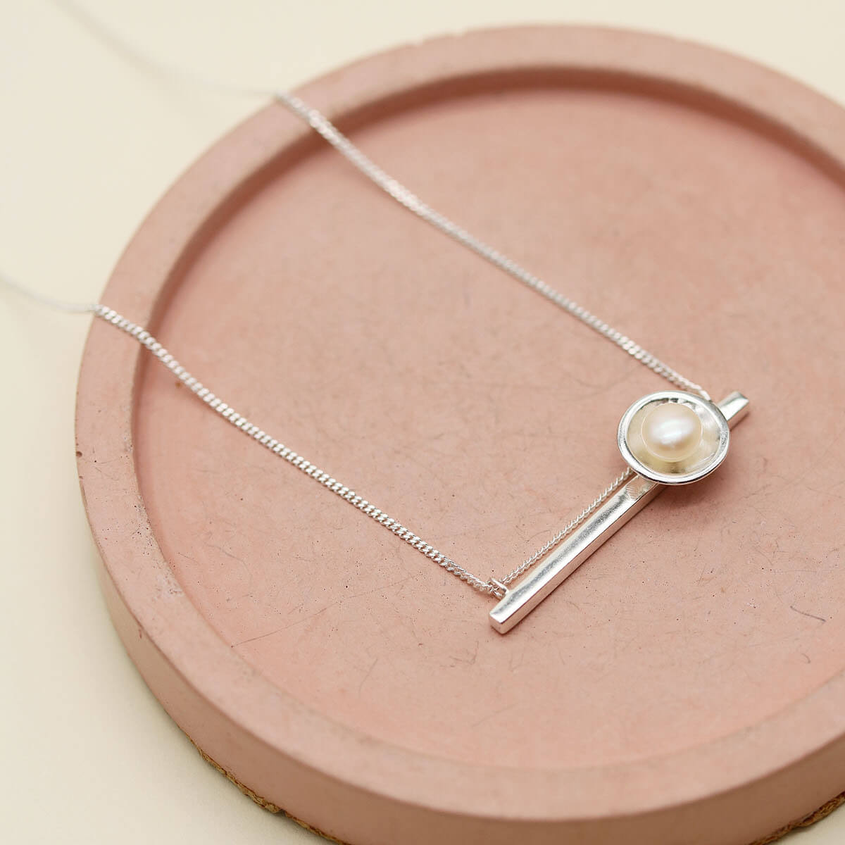 Sterling silver necklace with pearl pendant featuring a polished horizontal bar, freshwater pearl and delicate diamond-cut chain.