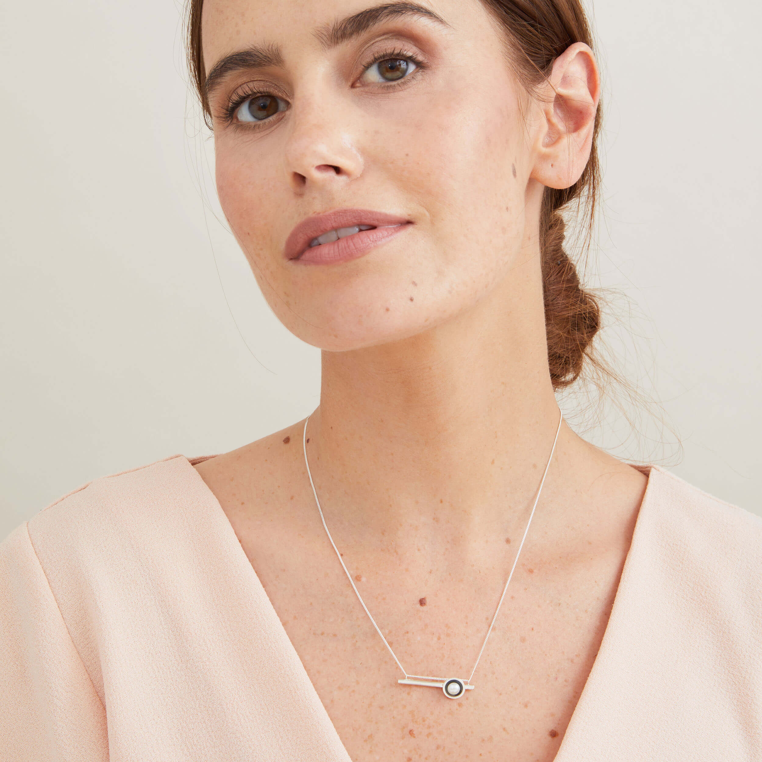 Black geometric pearl necklace worn with a white blouse, highlighting the elegant horizontal pearl pendant.
