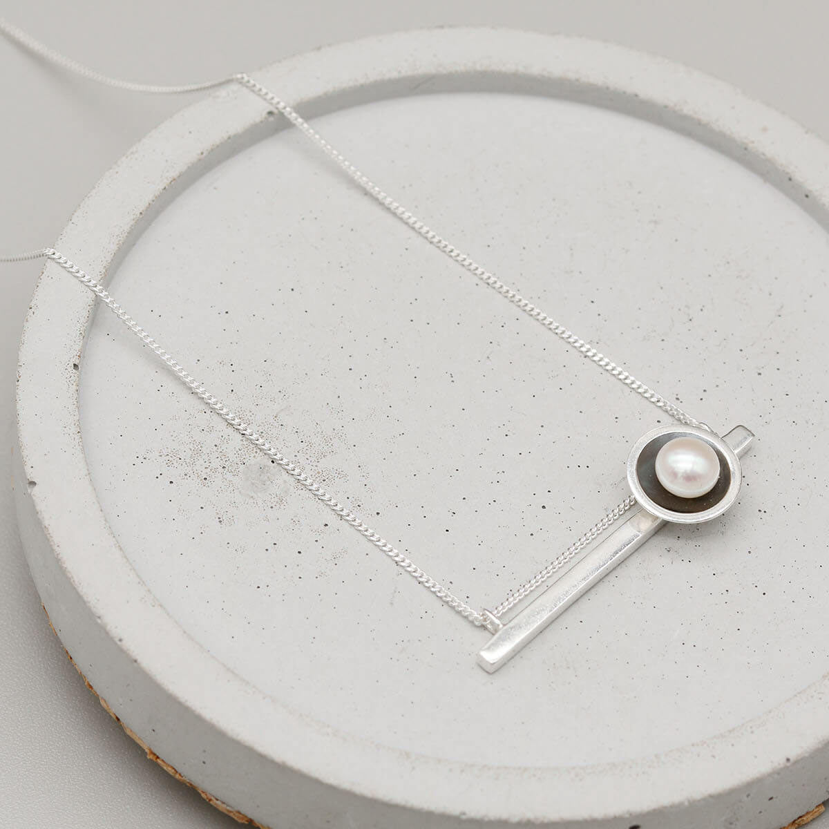 Contemporary black geometric pearl necklace with an Art Deco inspired horizontal bar pendant and freshwater pearl.