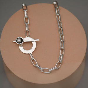 Contemporary chunky pearl necklace with sterling silver toggle clasp and large freshwater pearl displayed on a pink display stand.