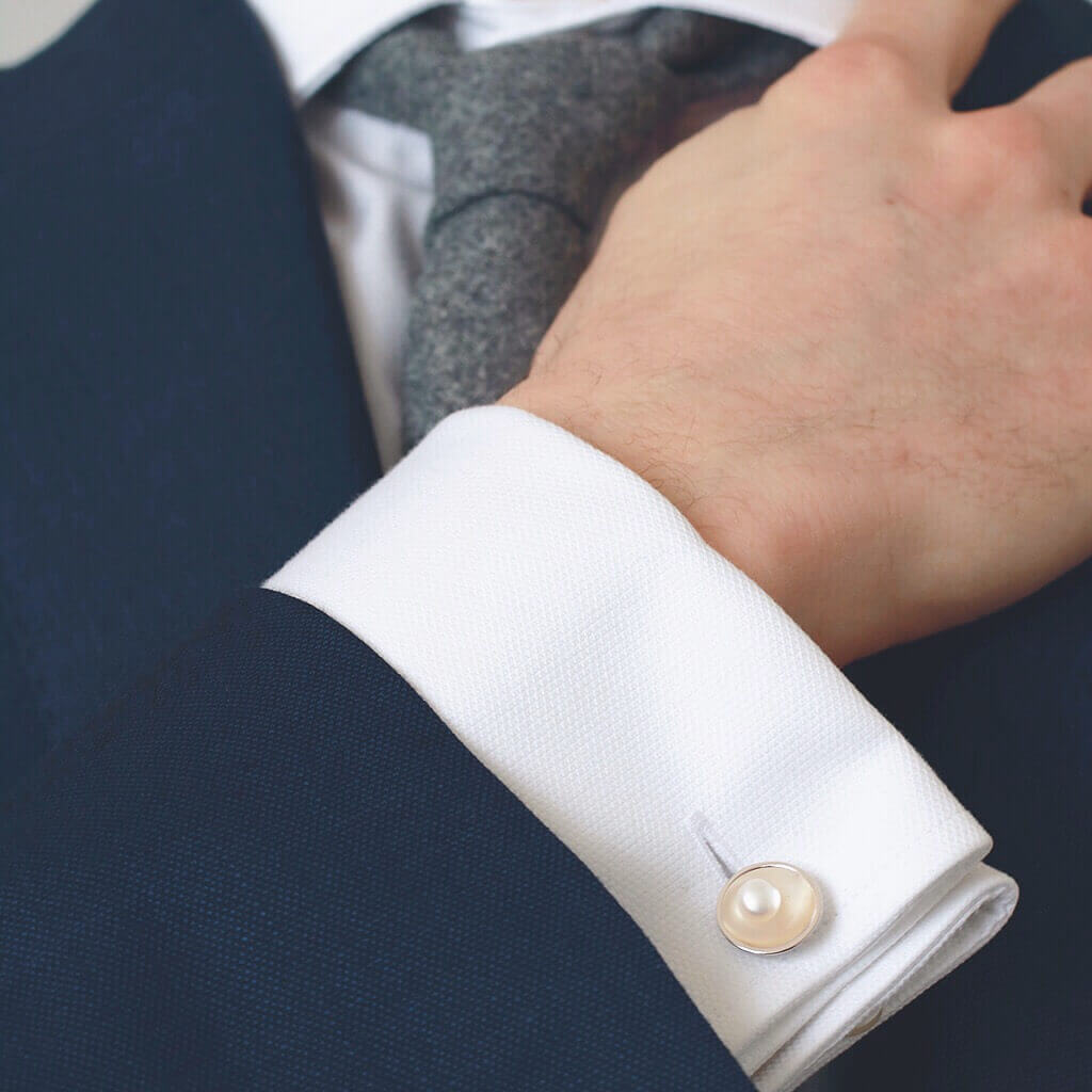 Freshwater pearl cufflinks in sterling silver worn on a white shirt cuff beneath a blue suit jacket.
