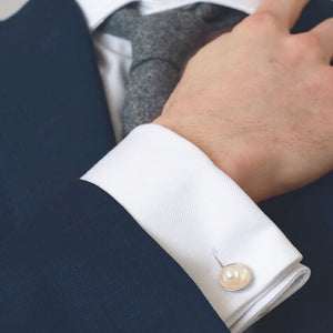 Freshwater pearl cufflinks in sterling silver worn on a white shirt cuff beneath a blue suit jacket.