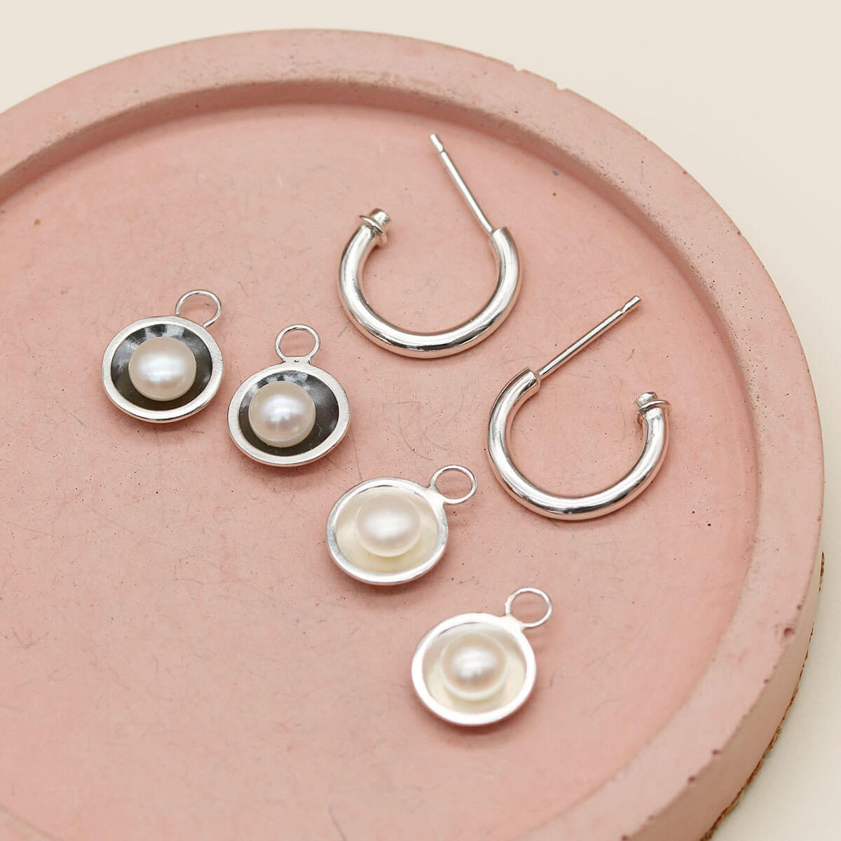 Sterling silver hoop earrings with pearls shown alongside the oxidised black pearl charm version for comparison.