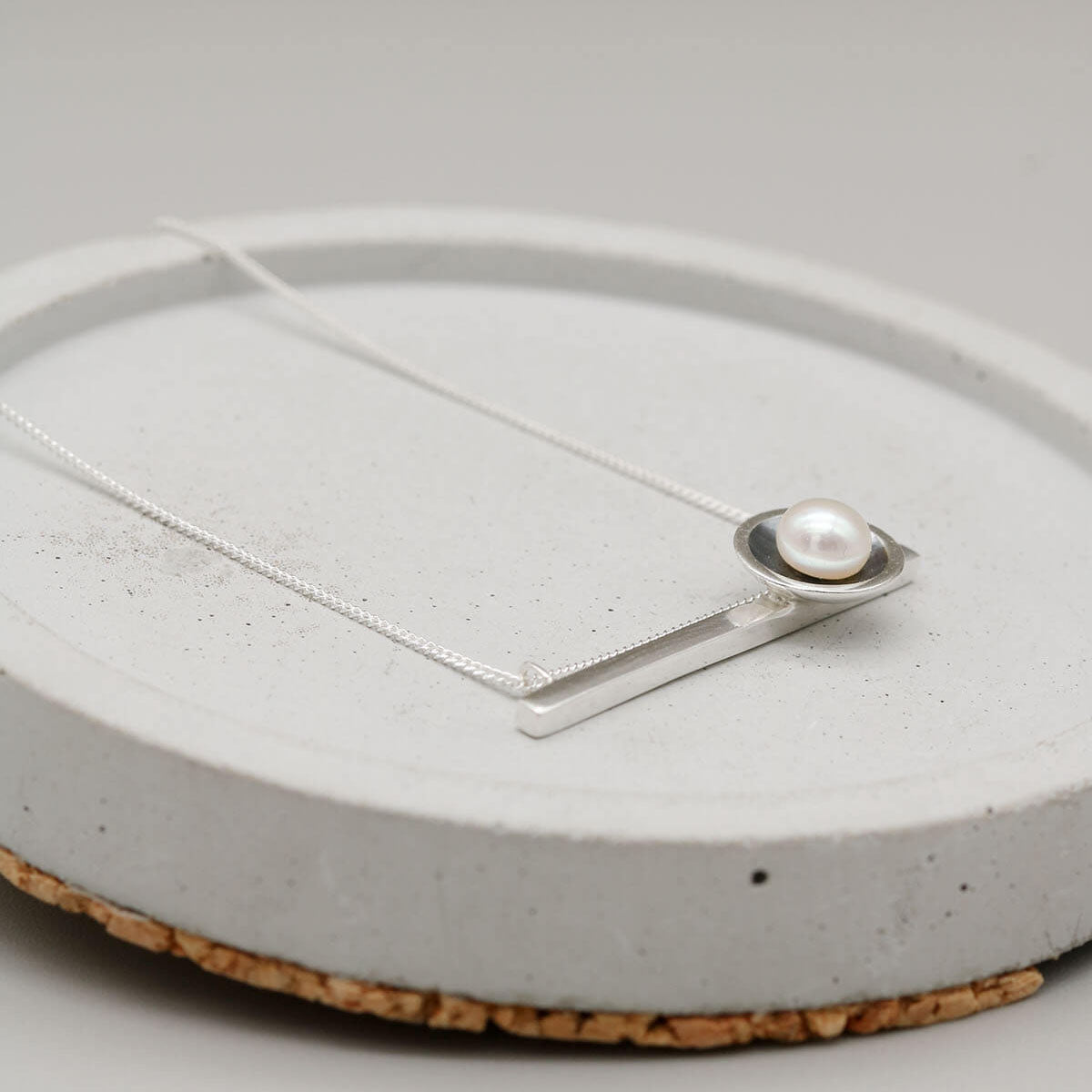 Black geometric pearl necklace featuring a horizontal sterling silver bar with a genuine freshwater pearl.