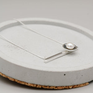 Black geometric pearl necklace featuring a horizontal sterling silver bar with a genuine freshwater pearl.