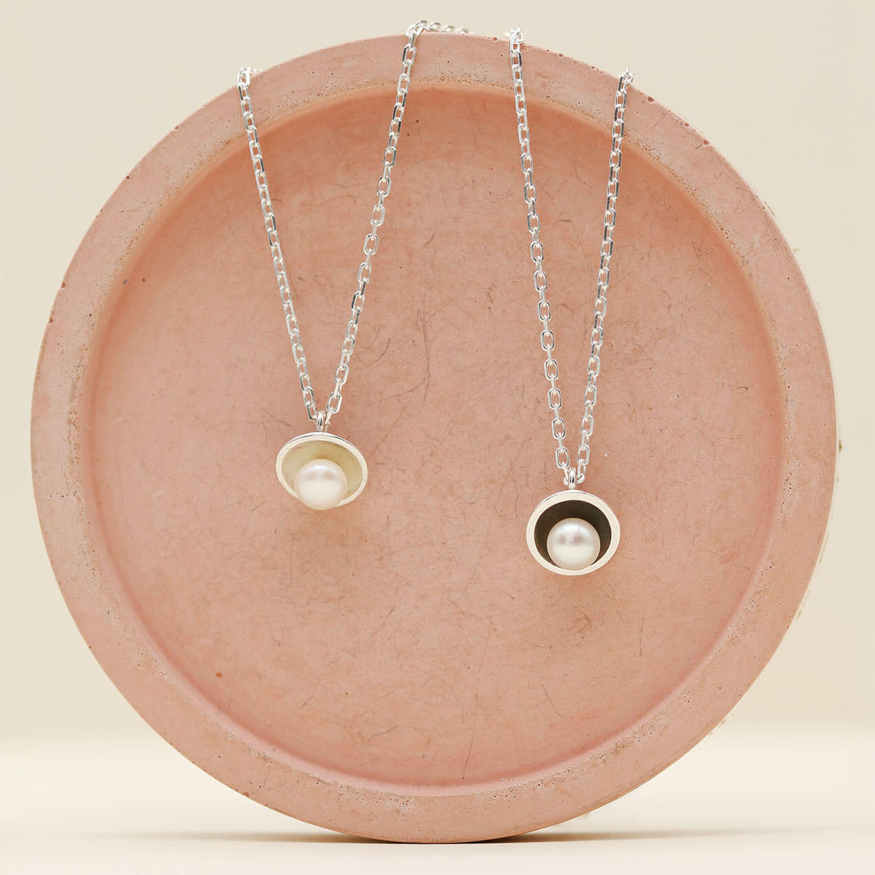 Comparison of polished sterling silver pearl pendant necklace alongside the oxidised black pearl pendant version, each set with a genuine freshwater pearl.