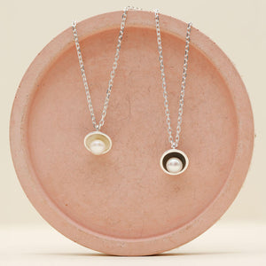 Comparison of polished sterling silver pearl pendant necklace alongside the oxidised black pearl pendant version, each set with a genuine freshwater pearl.
