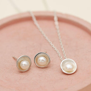 Matching silver pearl jewellery set featuring a handcrafted pendant necklace and pearl stud earrings.