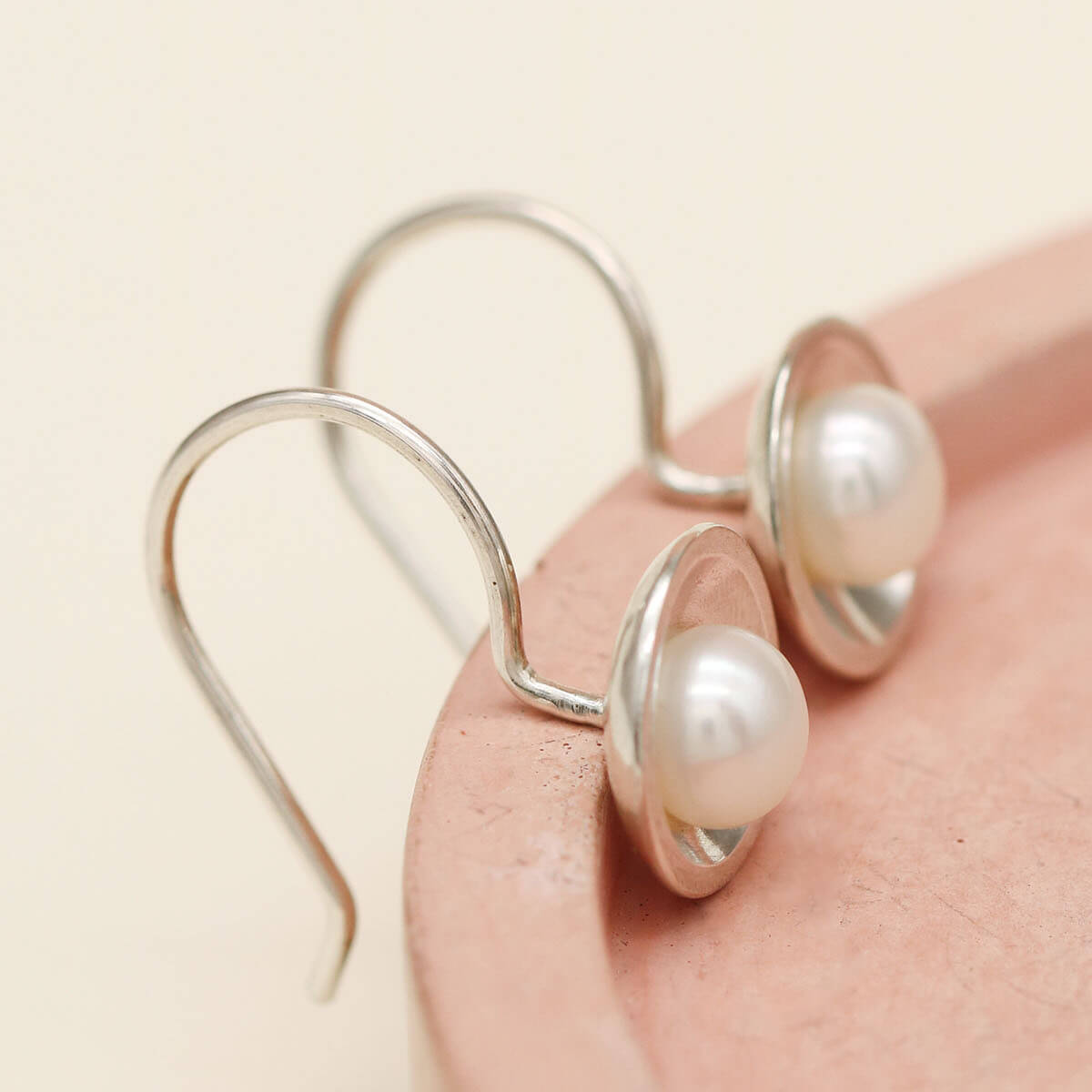 Close-up of sterling silver drop freshwater pearl earrings featuring polished silver domes and genuine freshwater pearls.
