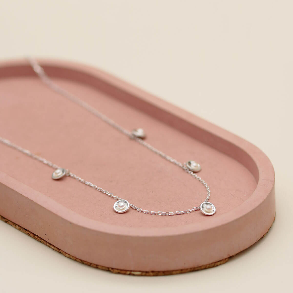 Close up of a sterling silver chain necklace with pearls showcasing polished silver settings and genuine freshwater pearls.