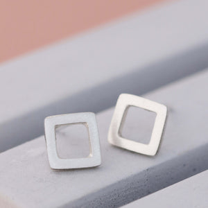 Matte square silver stud earrings on grey dish, minimalist square stud earrings