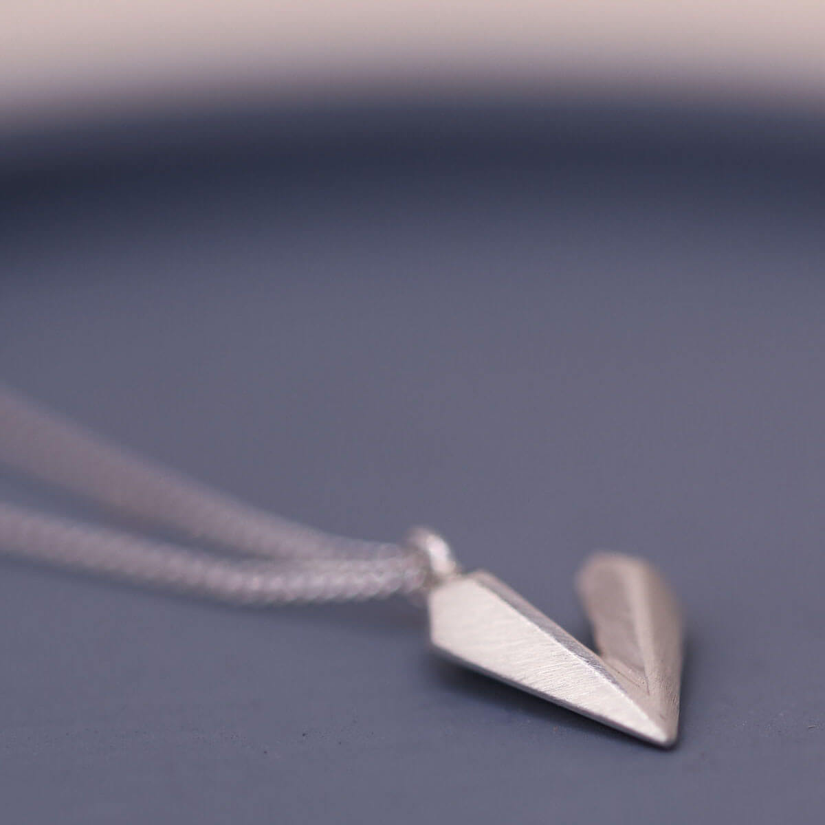Dainty heart necklace photographed on a blue dish, handmade sterling silver heart shaped necklace with elegant simple styling