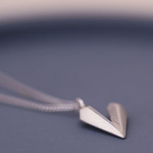 Dainty heart necklace photographed on a blue dish, handmade sterling silver heart shaped necklace with elegant simple styling