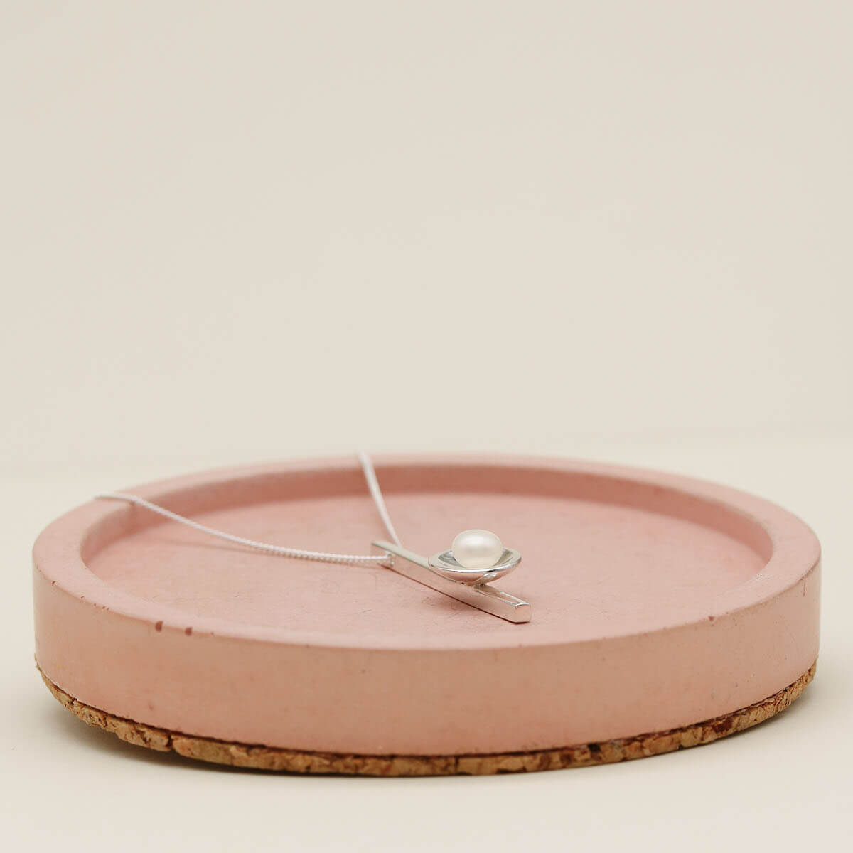 Handmade pearl bridal necklace displayed on a pink ceramic dish with a fine sterling silver chain.