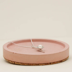 Handmade pearl bridal necklace displayed on a pink ceramic dish with a fine sterling silver chain.