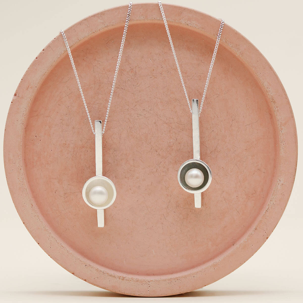 Sterling silver pearl bar necklace photographed alongside the oxidised black pearl bar necklace, comparing the polished and black finishes.