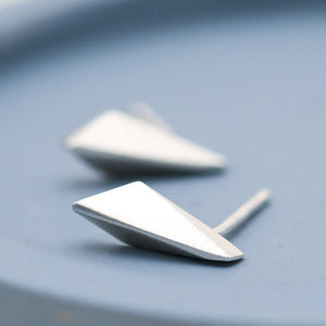 Sterling silver stud earrings with polished kite-shaped fronts on a deep blue dish, handmade small silver studs