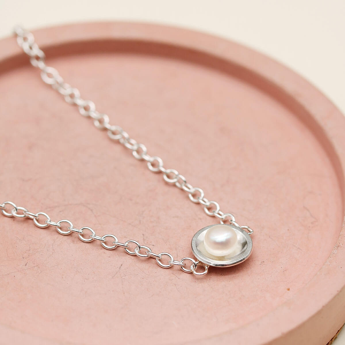 Close up of a handmade sterling silver pearl bracelet showcasing the polished silver setting and freshwater pearl.