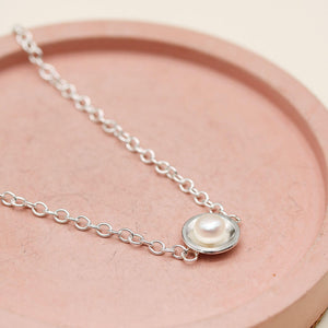 Close up of a handmade sterling silver pearl bracelet showcasing the polished silver setting and freshwater pearl.