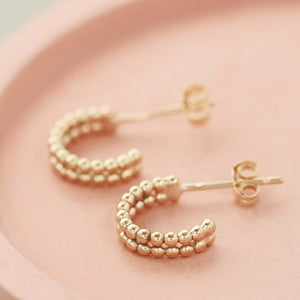 Small 9ct gold hoop earrings resting on a pale pink dish, ideal everyday jewellery or thoughtful Christmas gift.