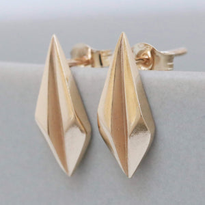 Gold art deco earrings shown flat on pale grey, solid gold geometric studs for everyday wear.