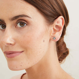 Model wearing Petite Tiny Pearl Stud Earrings handcrafted in oxidised sterling silver with genuine freshwater pearls. 