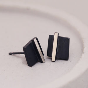 Small black stud earrings styled on a grey dish with modern minimalist detailing, thoughtful Mother’s Day gift.