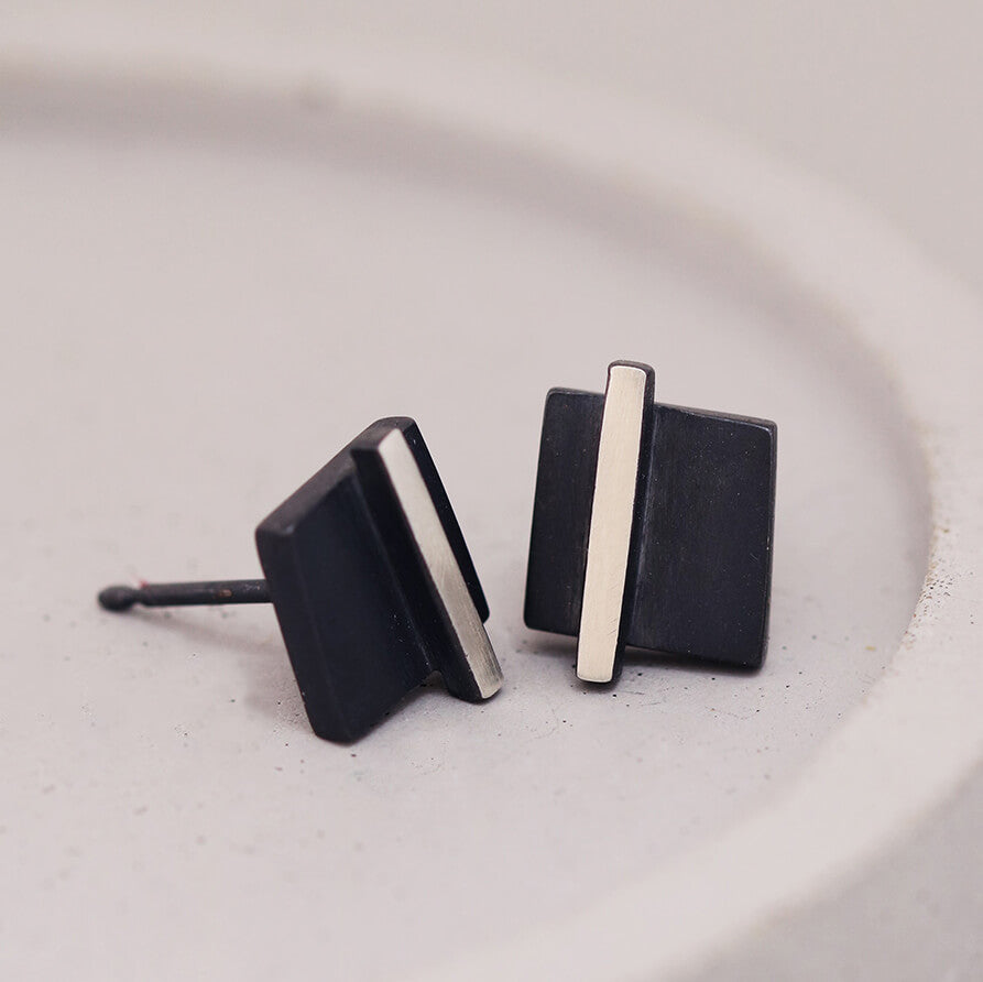 Small black stud earrings styled on a grey dish with modern minimalist detailing, thoughtful Mother’s Day gift.