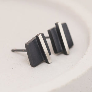 Angled view of small black stud earrings on a grey dish focusing on handcrafted sterling silver, ideal bridesmaid gift.