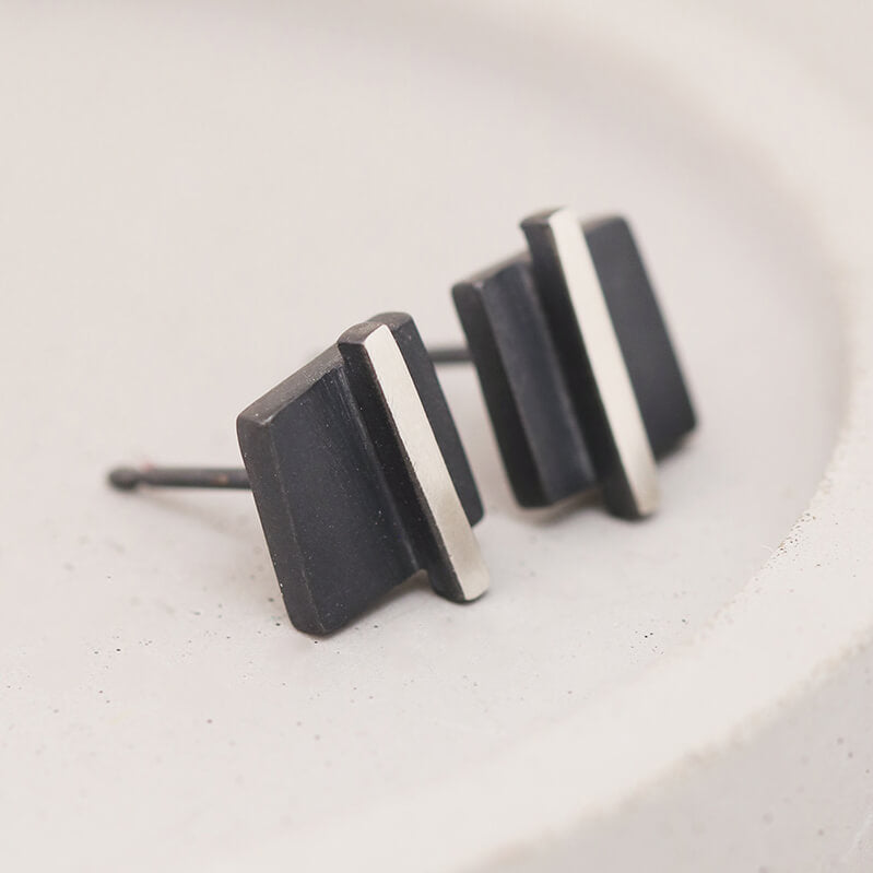 Angled view of small black stud earrings on a grey dish focusing on handcrafted sterling silver, ideal bridesmaid gift.