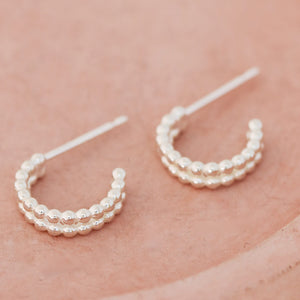 Small huggie hoop earrings handmade in sterling silver styled on a pink dish