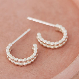 Sterling silver huggie earrings photographed on a pink dish, handmade small huggie hoop earrings