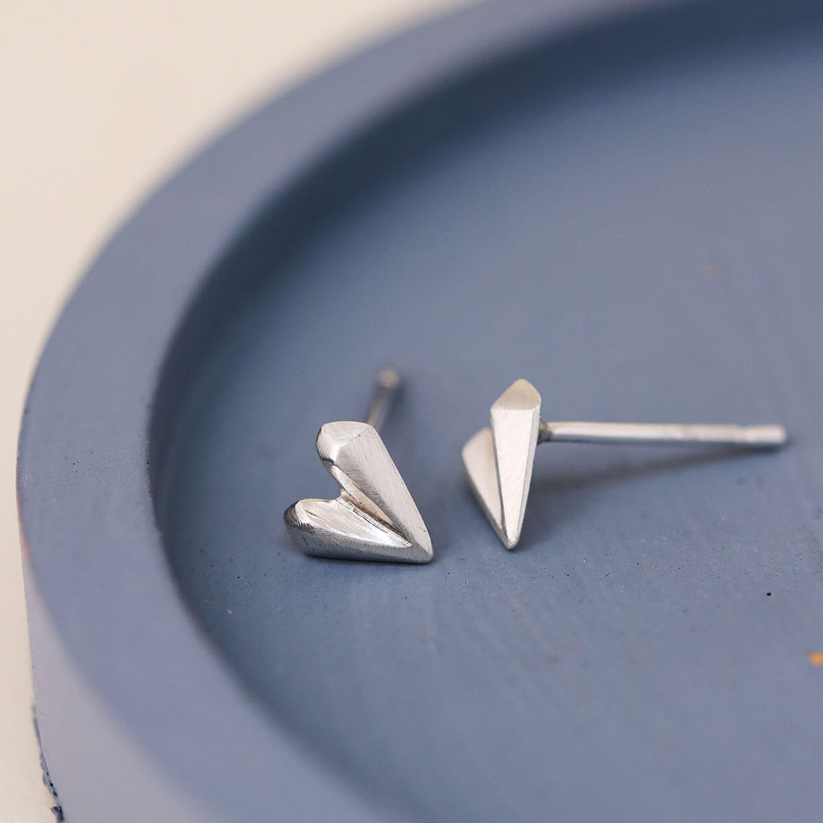 Pair of love heart earrings on blue dish, tiny sterling silver heart studs for everyday jewellery collection