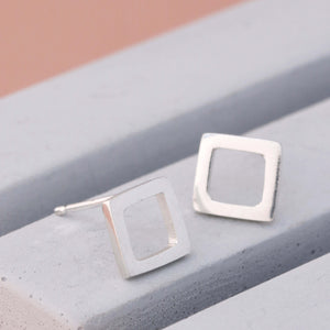Close-up of handcrafted square silver stud earrings in solid sterling silver