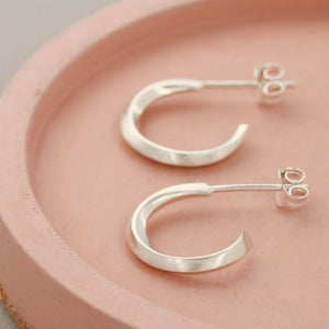 Handmade silver hoop stud earrings on a pink dish, classic sterling silver hoop earrings for women
