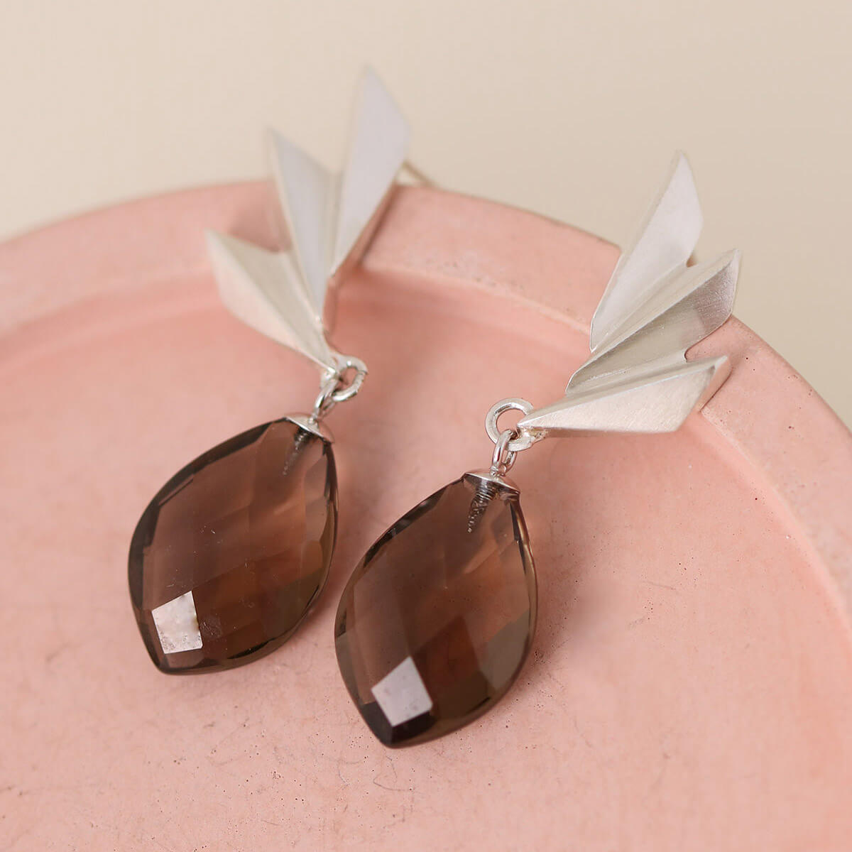 Smoky quartz earrings photographed on a pink background showing the textured fan shape; handmade art deco statement earrings for jewellery lovers.