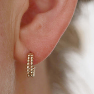 Model wearing small 9ct gold hoop earrings, showing the tiny double-hoop style of these 9 carat gold hoops for an elegant everyday look.