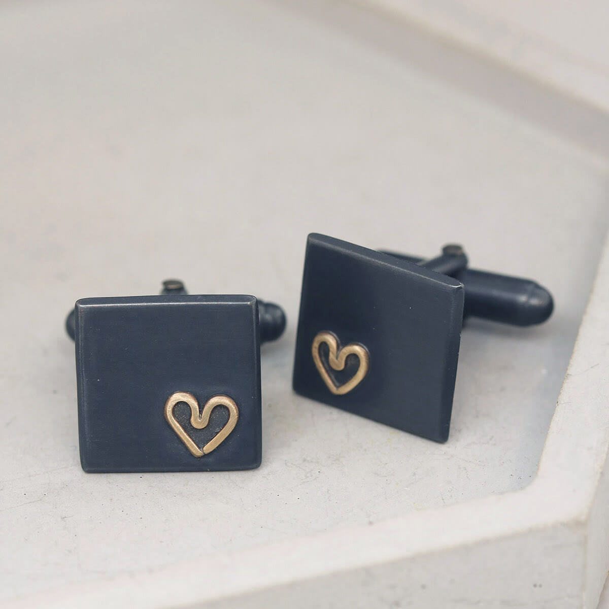 Silver cufflinks with gold heart detail on grey dish, classic special anniversary gifts for husband, free delivery included.
