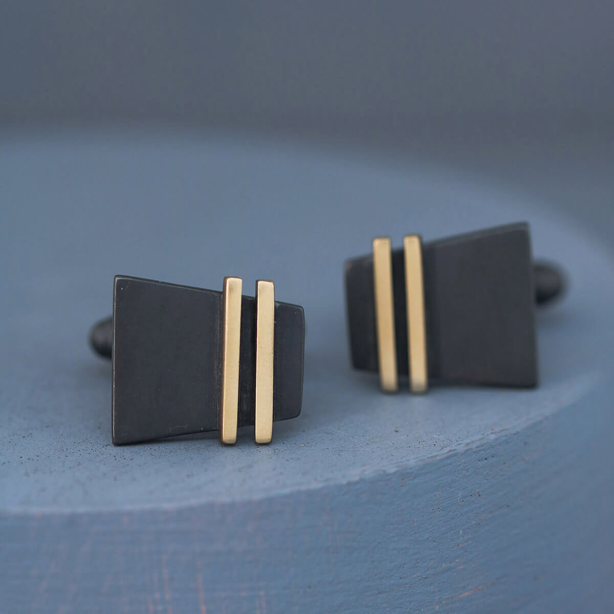 Front view of Black and Gold cufflinks against deep blue backdrop, showcasing craftsmanship, perfect special cufflinks for husband anniversary gifts.