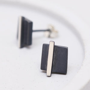 Silver and black earrings laid flat on a grey dish highlighting the geometric shape, perfect thank-you gift.